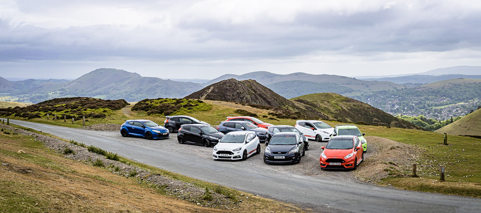 Group of cars parked on a hillside.